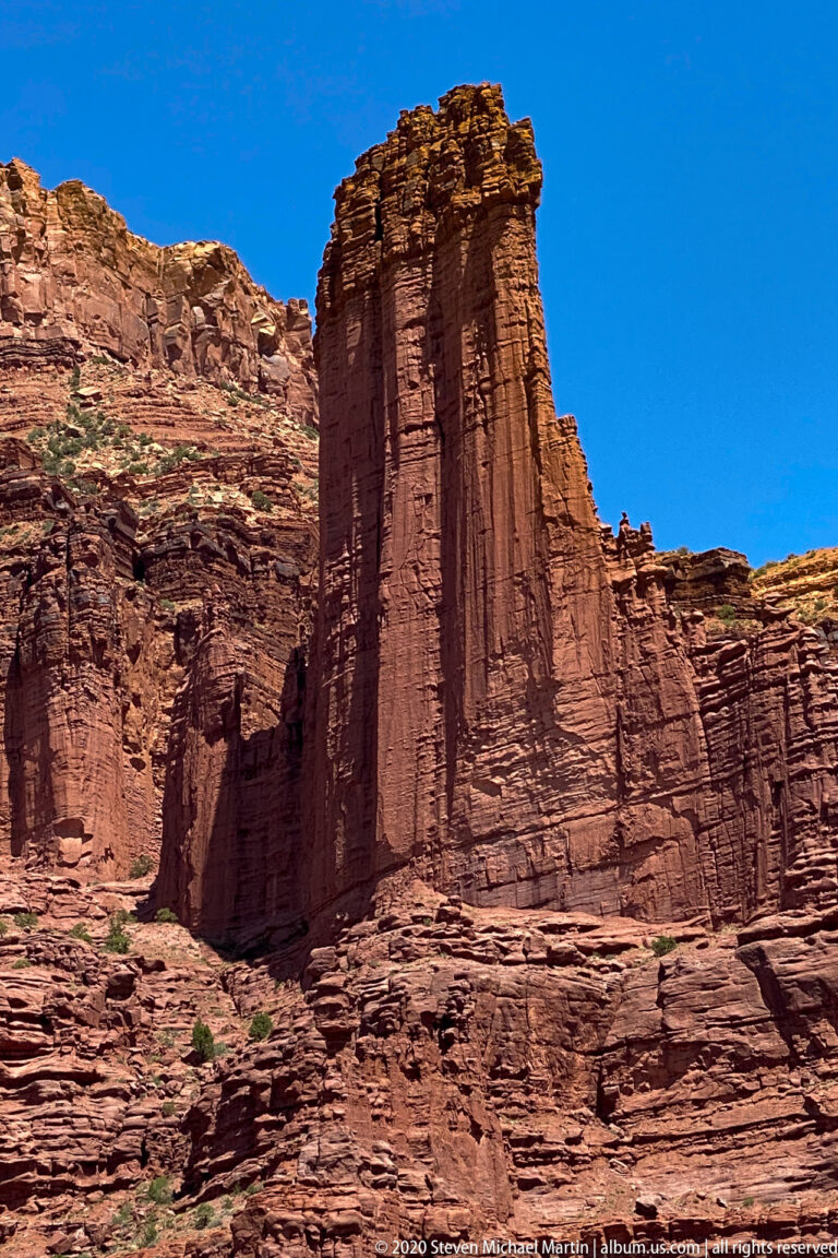 A large isolated red sandstone tower rises against open sky above the surrounding desert terrain.