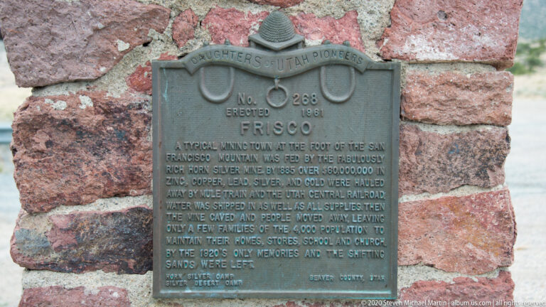A Daughters of Utah Pioneers plaque about Frisco is mounted on a rough stone wall.