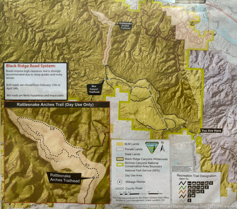 A printed relief map shows roads, land boundaries, a Rattlesnake Arches Trail inset, and a “You Are Here” marker.