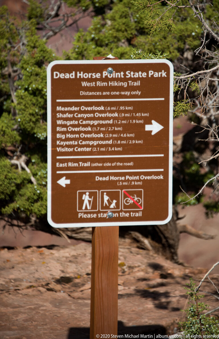 A brown park sign lists West Rim Trail destinations, distances, and directions at Dead Horse Point.