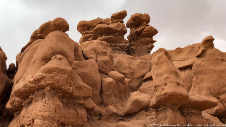 Rounded orange sandstone hoodoos and stacked ledges overlap in a close view of the rock cluster.
