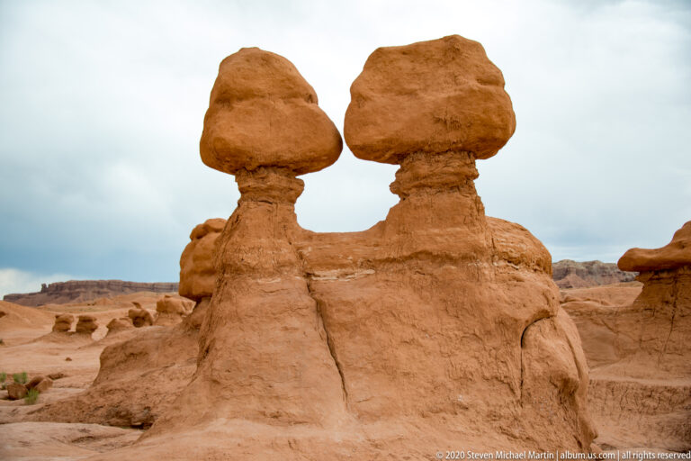Two broad-capped sandstone pedestals stand side by side on a shared base.