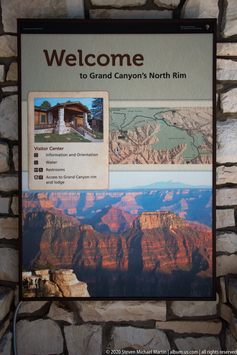 A North Rim welcome sign displays a map, visitor services, a visitor-center photo, and canyon panorama.
