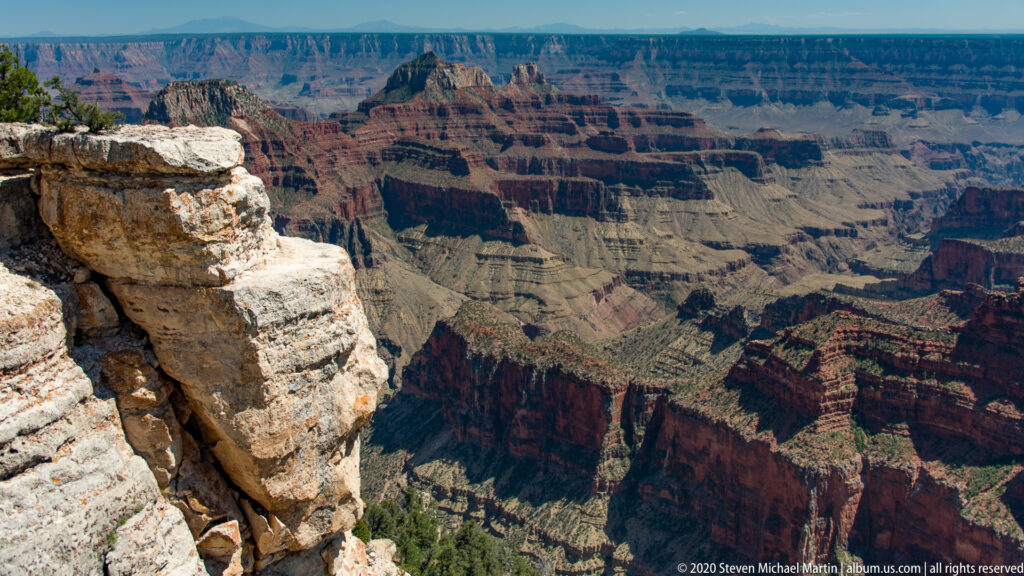 Pale broken rim rock frames red and tan canyon terraces in the distance.