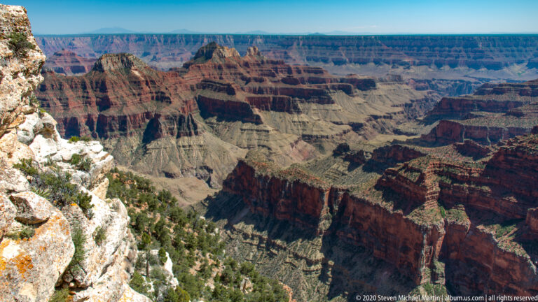 Pale rim rock borders a wide panorama of red cliffs, gray ledges, and deep ravines.