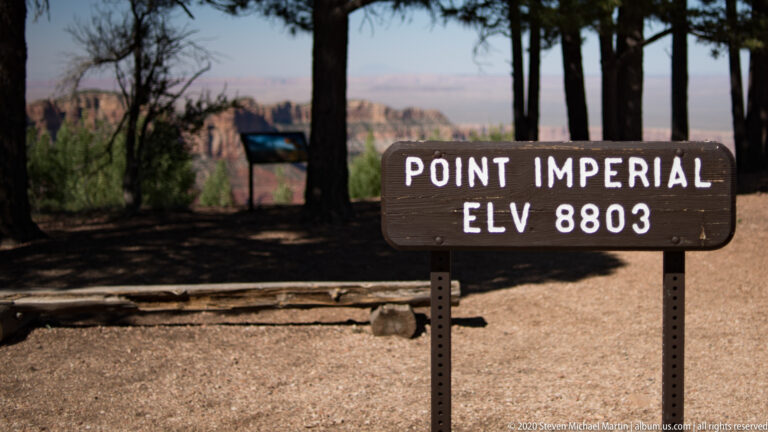 A brown sign marks Point Imperial at 8,803 feet, with canyon scenery behind.