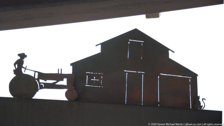 A barn silhouette with a wagon and small figure stands against a bright sky.