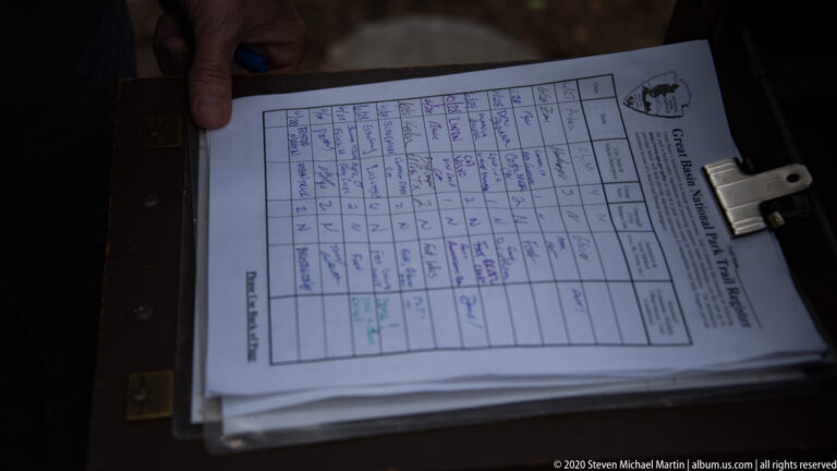 A hand holds a clipboard with a handwritten Great Basin National Park visitor log.