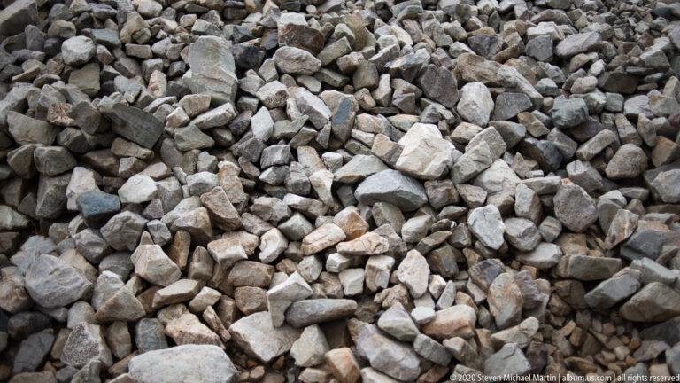 A dense close-up of angular gray and tan stones covering a rocky slope.