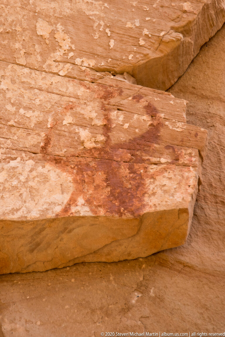 A broad reddish-brown stain marks a flat layered sandstone slab.