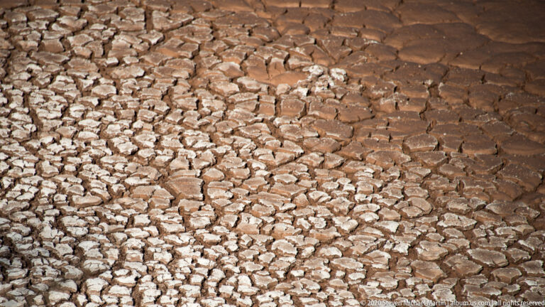 Close view of raised, angular clay plates separated by dark reddish cracks.