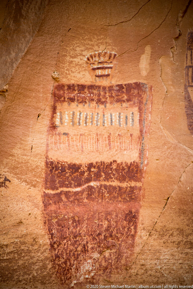 A large rectangular painted figure has repeated vertical marks in its lighter center and a small motif above.