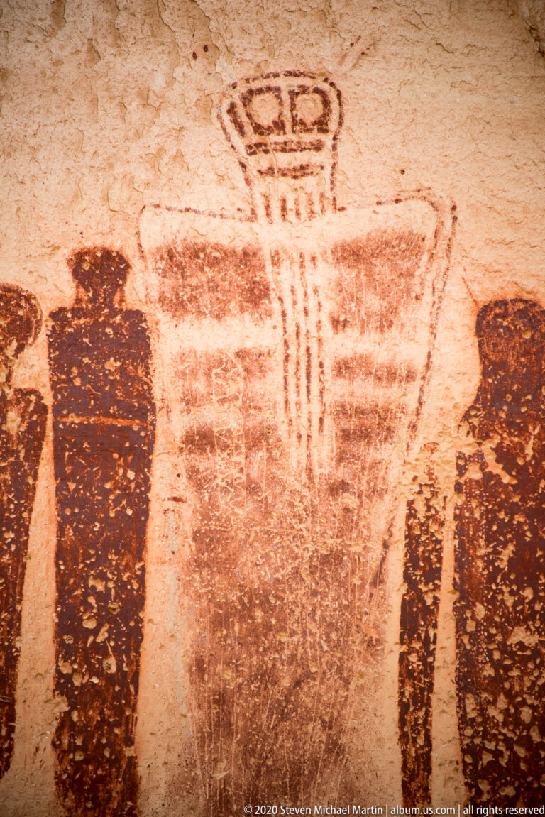 A close view of a banded figure with vertical marks and a looped top, flanked by cropped silhouettes.