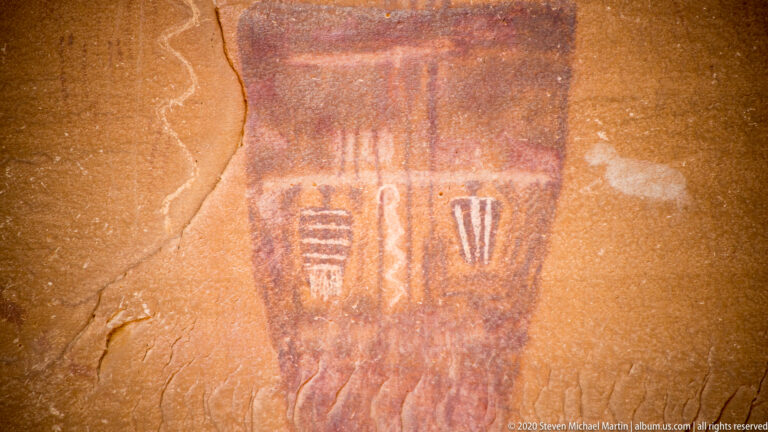A dark tapered pictograph contains pale striped, looped, and paired marks within its central field.