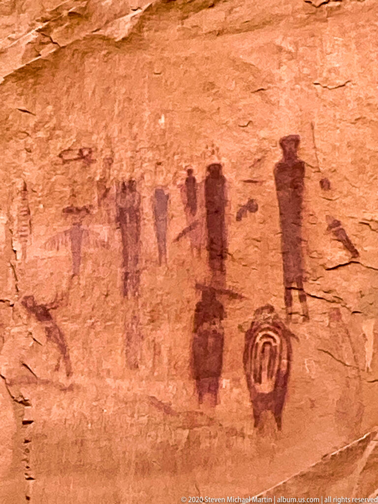 A close sandstone panel shows red elongated figures, faint marks, and a large outlined oval motif.