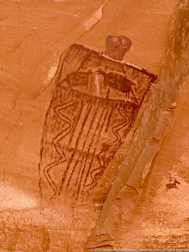 A large tapered pictograph contains parallel stripes and angular patterns, with a small rounded form above it.