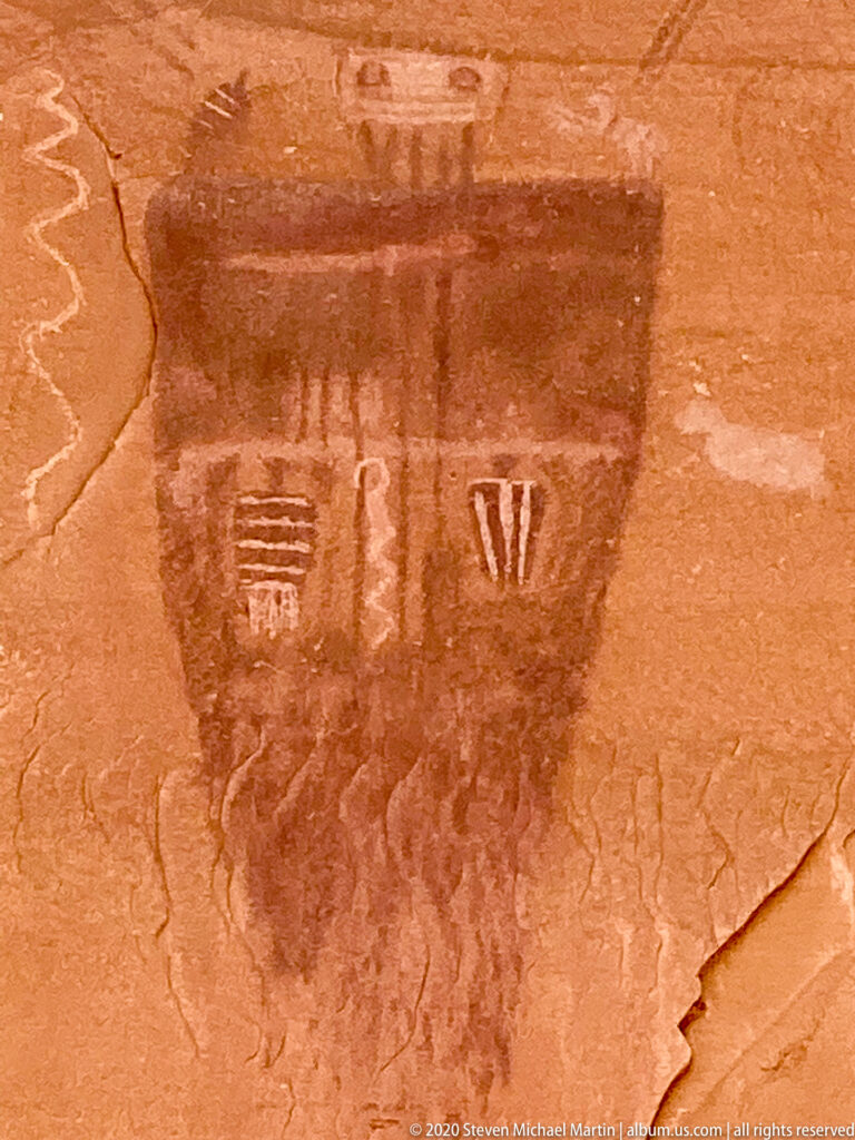 A broad dark pictograph contains several small pale symbols in a lighter band near its center.