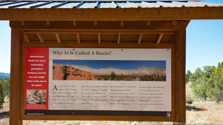 A wooden kiosk displays a “Why Is It Called a Basin?” panel with a cliff panorama and text.