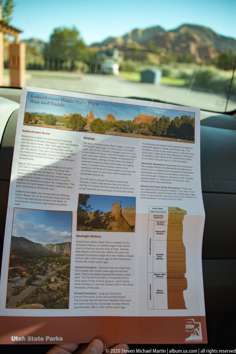 A Utah State Parks guide with landscape photos and a geological diagram rests on a car dashboard.