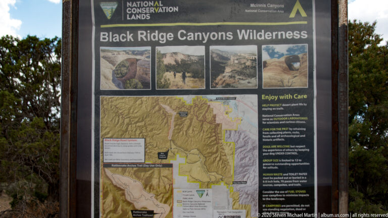 A wilderness sign shows canyon photographs, a large map, and “Enjoy with Care” guidance.
