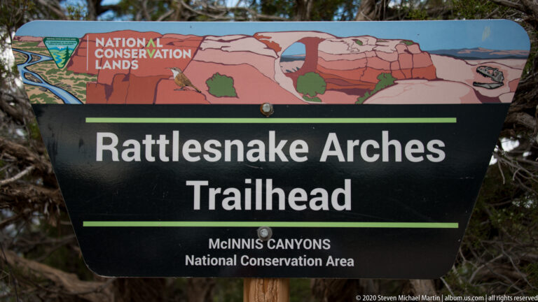 A brown sign directs hikers right to Lower Rattlesnake Arches Trail and left to Pollock Trailhead.