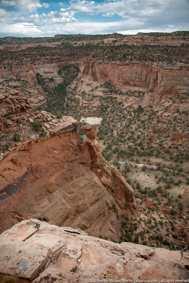 A broad sandstone canyon extends from a pale foreground rim to distant mesas.