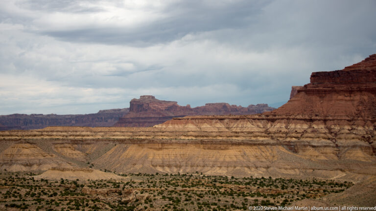 Red, cream and ochre rock bands form a broad escarpment above scrubland.