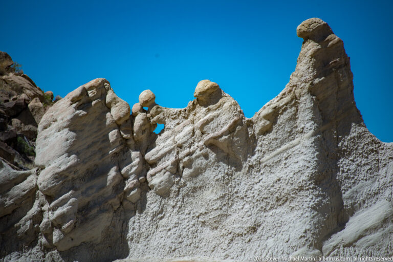 The narrow central pinnacle rises above a broken pale ridge with smaller rounded spires.