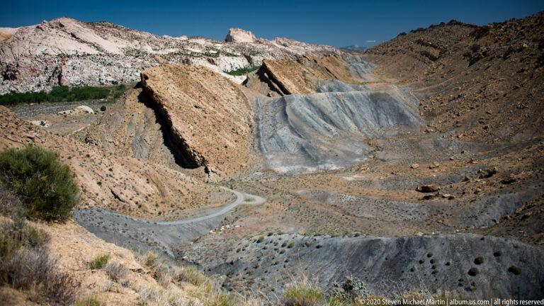 The road bends across the bottom of the open valley toward a light ridge beneath dark hills.