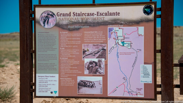 A monument wayside sign combines road guidance, emergency contacts, historic photographs, and a route map.
