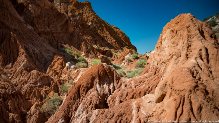 Rounded red sandstone ridges fill a narrow passage between taller rock walls.
