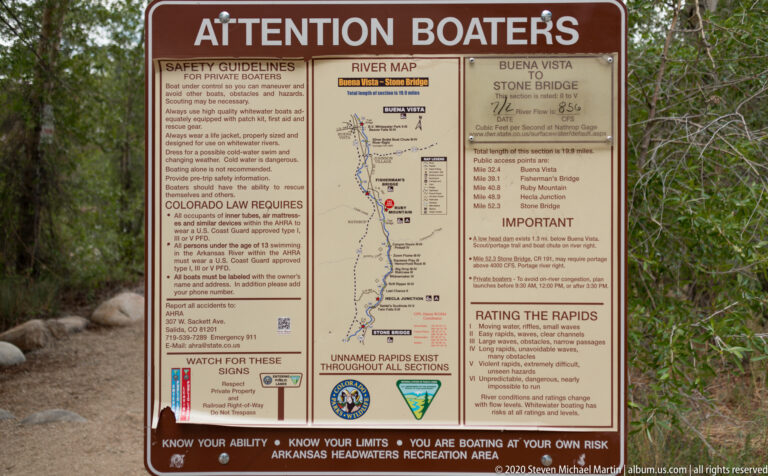 A large “Attention Boaters” sign displays river safety rules, a route map, access points, and rapid ratings.