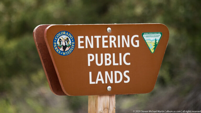 A brown “Entering Public Lands” sign displays Colorado Parks and Wildlife and land-management emblems.