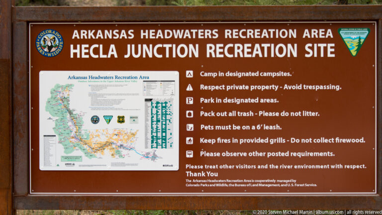 A Hecla Junction board displays a recreation-area map and visitor rules beside the river.