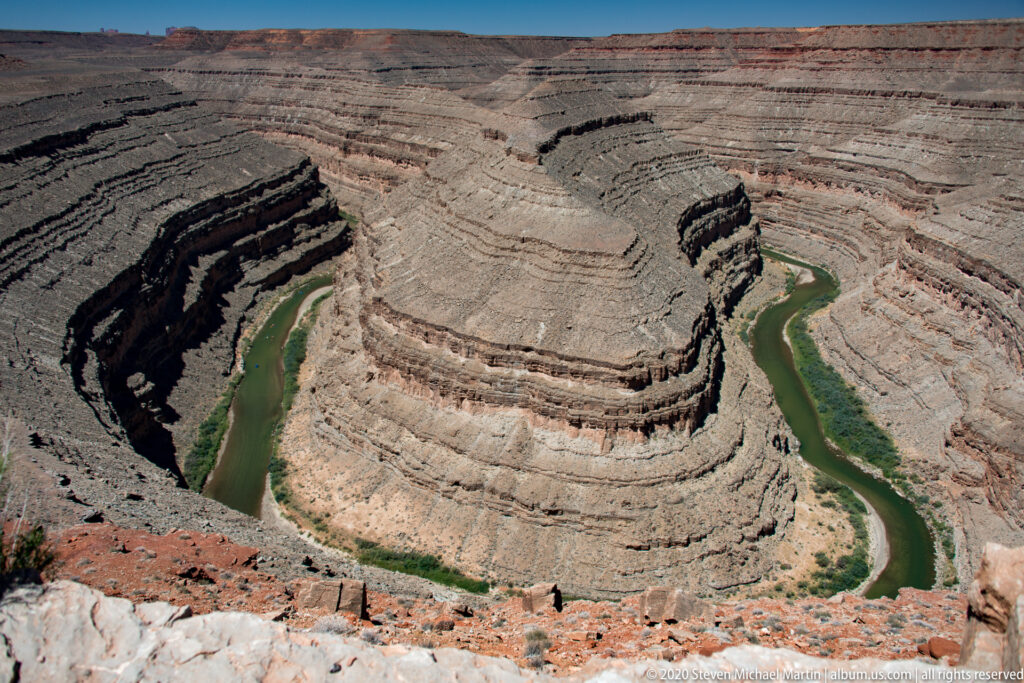 A green river arcs around a pale layered promontory between steep canyon walls.