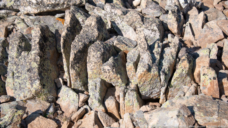 Fractured gray and tan boulders with pale lichen fill a close rocky view.