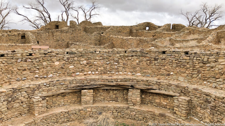 Excavated circular masonry kiva below surrounding stone room blocks at Aztec Ruins.