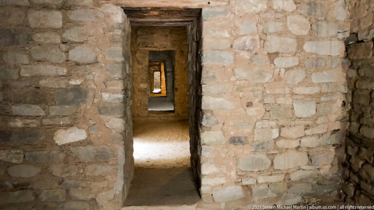 Multiple rectangular doorways align through a sequence of thick stone-walled rooms, with light visible at the far end.