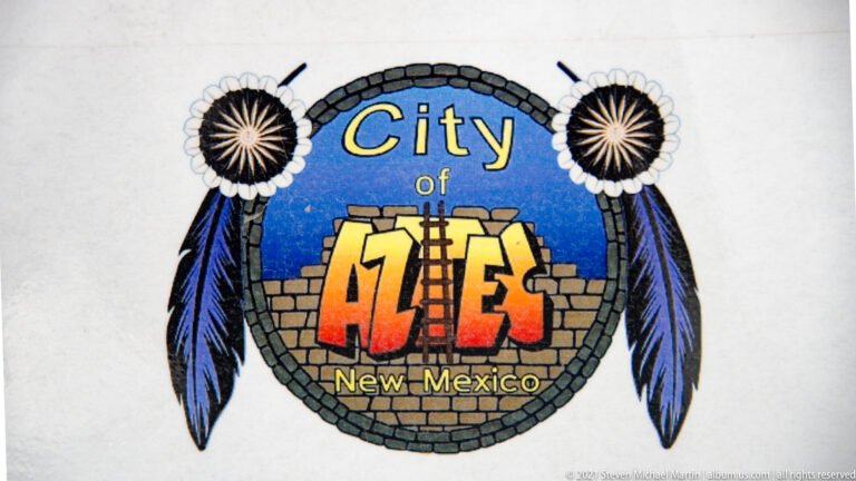 Colorful City of Aztec, New Mexico emblem with feathers, rosettes, and stylized masonry border.