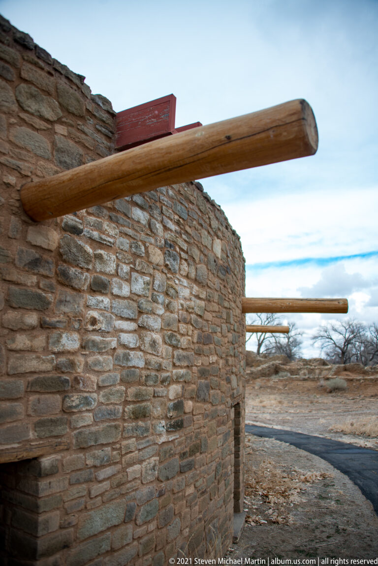 Round wooden vigas project from the curved, thin-coursed stone wall of the reconstructed Great Kiva.