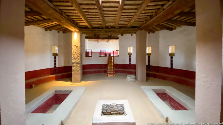 Wide view of the reconstructed Great Kiva showing paired floor recesses, central feature, supports, and timber roof.