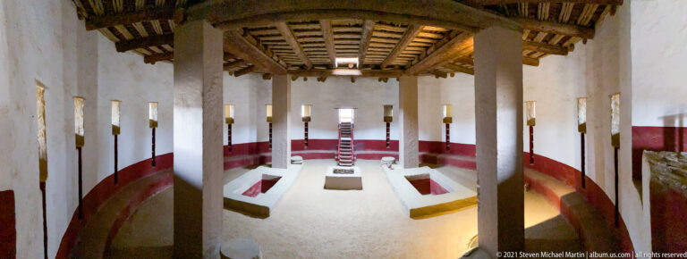 Oblique elevated view into the reconstructed Great Kiva, with curved wall, floor features, supports, and timber ceiling.