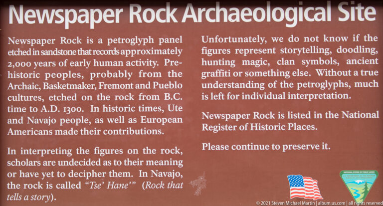 Close view of a brown interpretive sign describing Newspaper Rock and asking visitors to preserve the site.