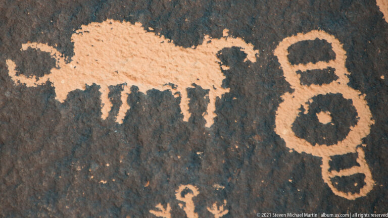 A broad pale figure lies beside a vertical pair of ringed circles, with smaller carvings below.