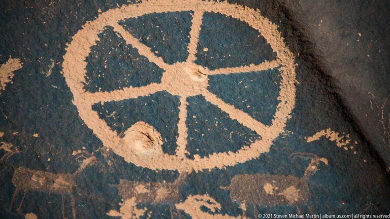 A large circular petroglyph is divided by radiating spokes that converge at a central point.