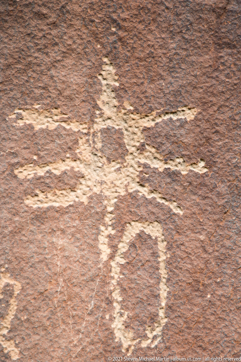 A long pale outline and a separate circular mark cross a reddish sandstone surface.