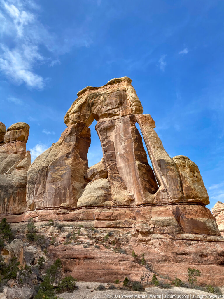 A low frontal view looks up through Druid Arch’s tall opening and between its sandstone supports.