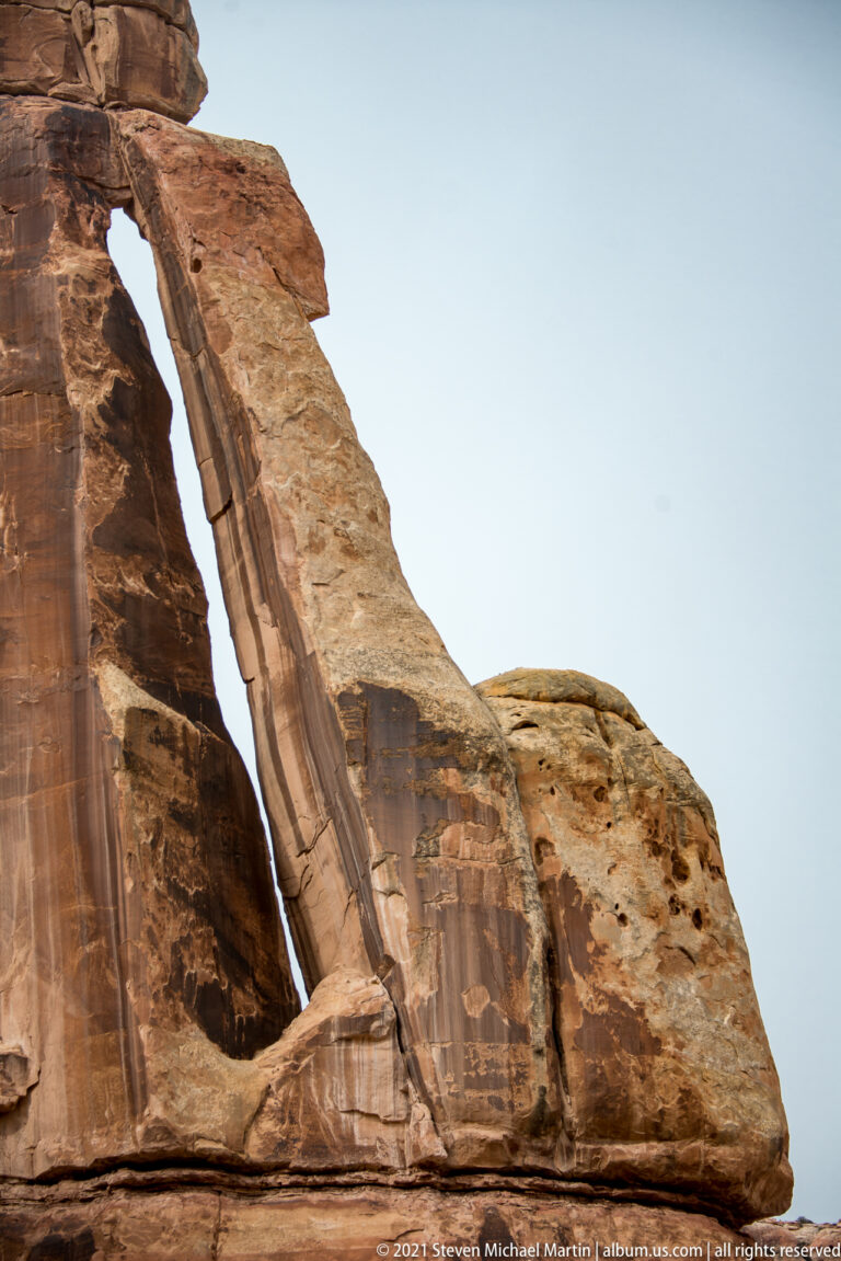A sloping sandstone support fills the view beside a narrow dark opening, with the arch capstone cropped above.