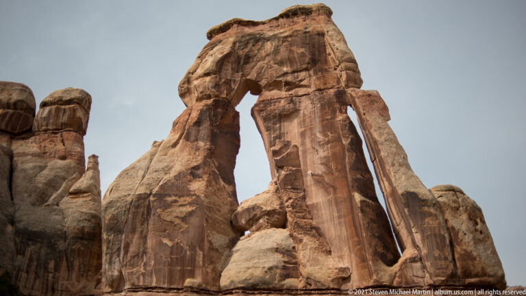 A close upward view shows Druid Arch’s capstone over a tall support and dark opening.