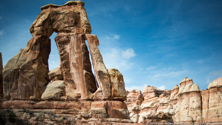 Druid Arch rises at left while smaller sandstone towers continue across the right side of the canyon.